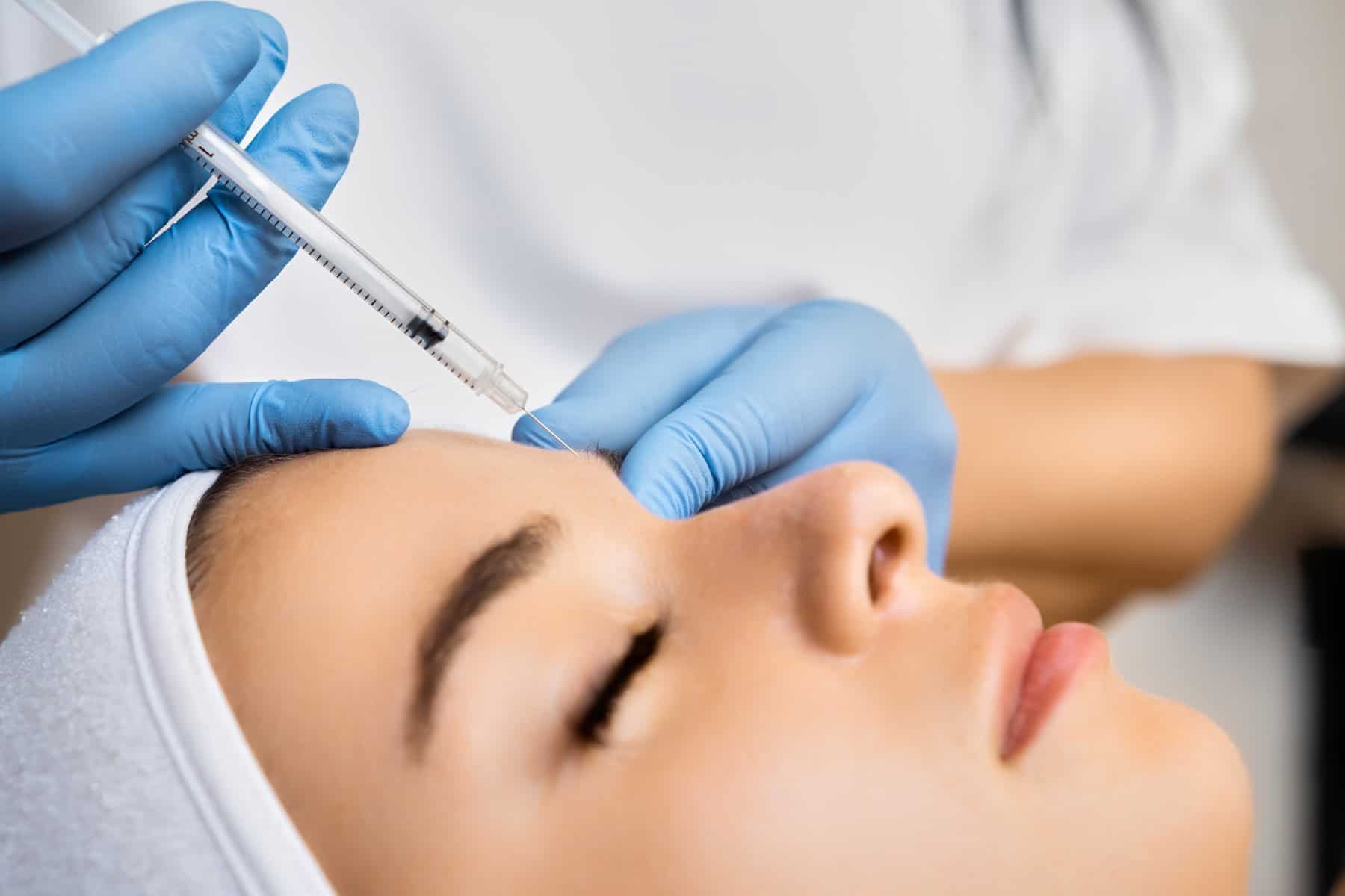 Close-up van een cosmetische specialist die een botox injectie toedient aan het voorhoofd van een patiënt.