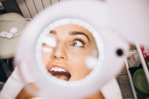 female face through the magnifying lens in a beauty salon