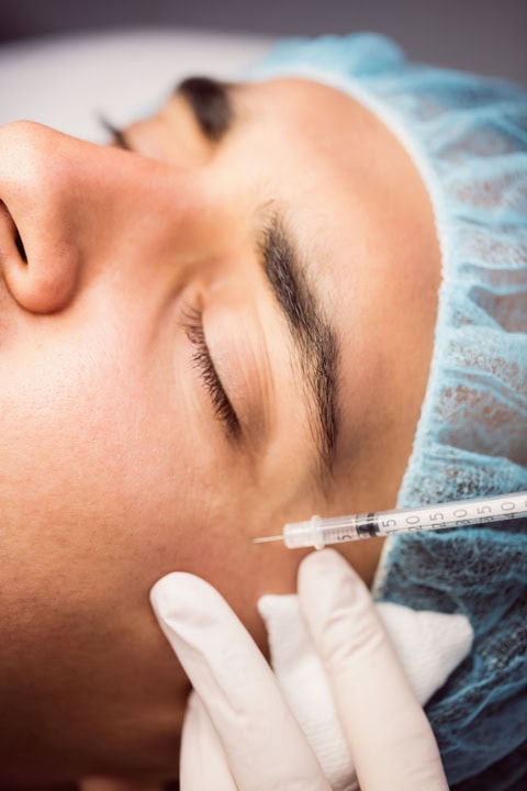 man receiving botox injection on his face at clinic